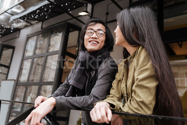 Happy asian young loving couple standing near cafe outdoors Stock photo © deandrobot