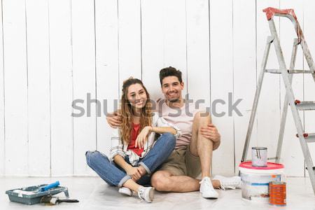 Happy multiethnic young couple renovating home and using mobile phone Stock photo © deandrobot