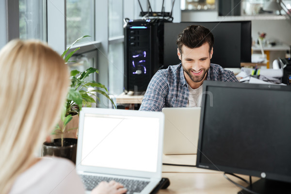 Happy two colleagues in office coworking while using laptops Stock photo © deandrobot