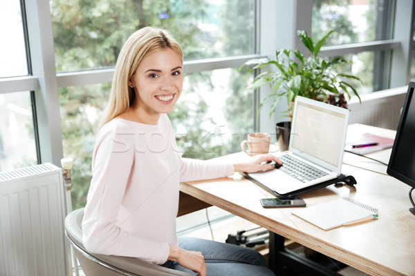 Cheerful lady sitting in office coworking using laptop Stock photo © deandrobot