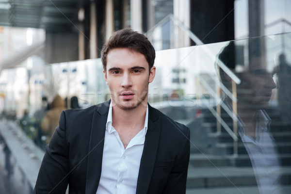 Concentrated young businessman walking near business center Stock photo © deandrobot