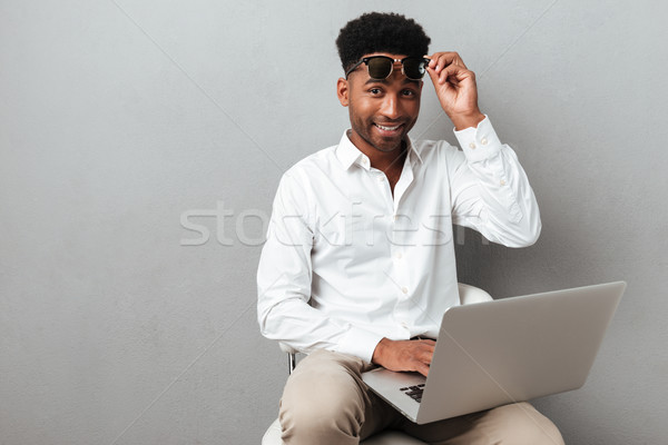 Smiling happy african man holding laptop computer on his lap Stock photo © deandrobot