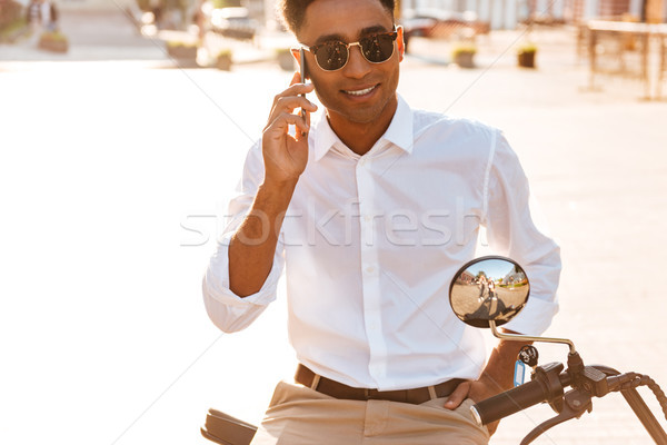 Carefree african man in sunglasses sitting on modern motorbike Stock photo © deandrobot