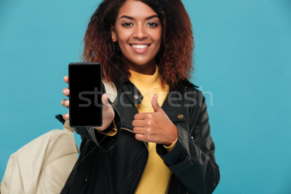 Cheerful african woman student showing display of mobile phone Stock photo © deandrobot