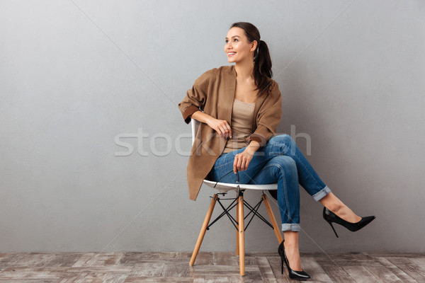 Portrait of a cheery asian woman sitting on a chair Stock photo © deandrobot