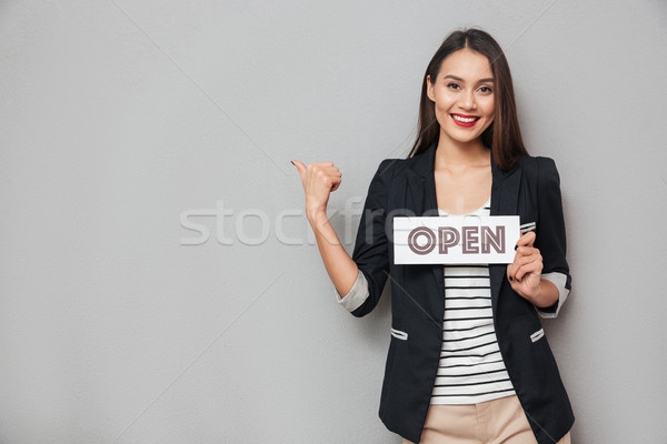Stock photo: Pleased business woman holding nameplate open and pointing on copyspace