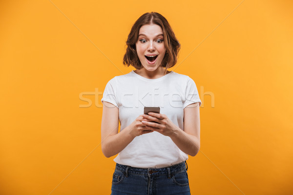 Excited young woman chatting by mobile phone Stock photo © deandrobot