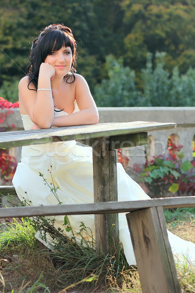 Stock photo: Girl in the wedding dress sitting on the bench