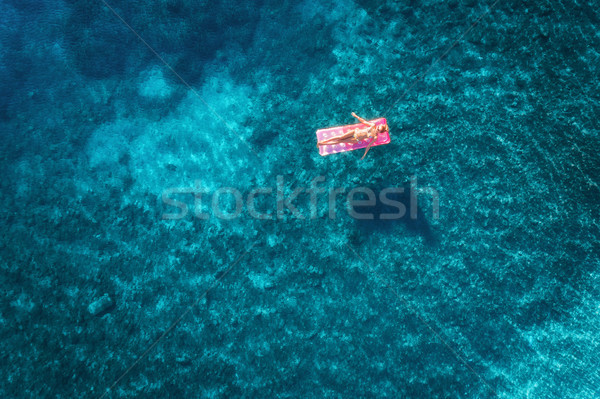 Aerial view of young woman swimming on the pink inflatable mattr Stock photo © denbelitsky