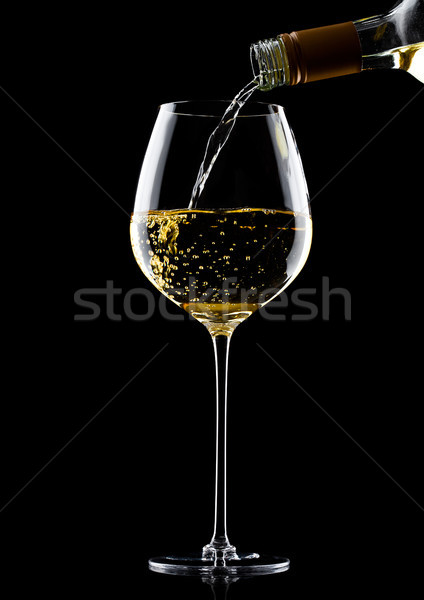 Pouring white wine from bottle to glass on black Stock photo © DenisMArt