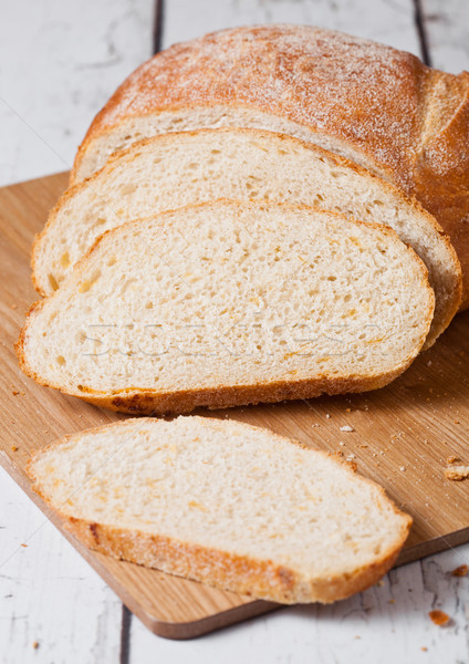 Freshly baked bread loaf with pieces on wood board Stock photo © DenisMArt