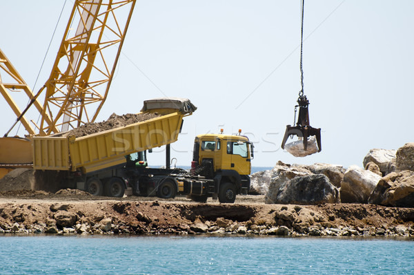 Building a dike. Cranes and excavator put stones Stock photo © deyangeorgiev