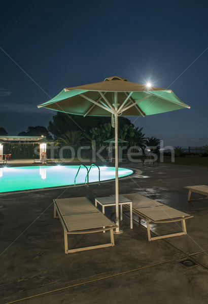Stock photo: Pool, sunbeds and umbrellas at night