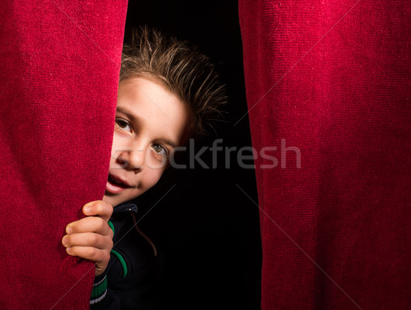 Stock photo: Child appearing beneath the curtain