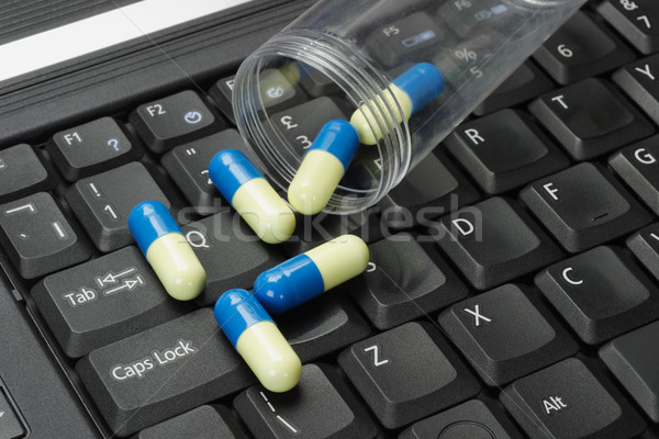 Stock photo: Pills spilled on black laptop keyboard