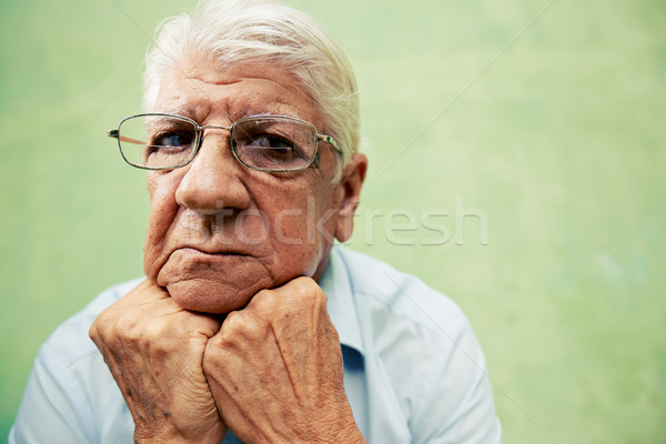Portrait of serious old man looking at camera with hands on chin Stock photo © diego_cervo