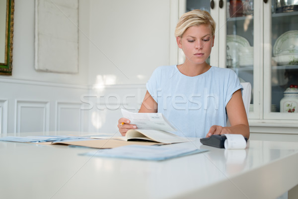 Young woman checking bills and doing budget at home Stock photo © diego_cervo
