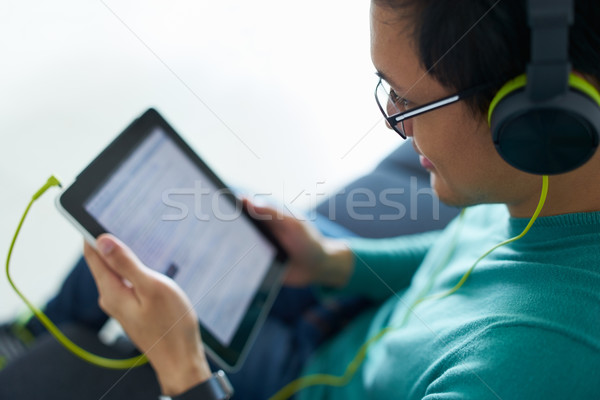 Chinese Man With Green Headphones Listens Podcast Tablet PC Stock photo © diego_cervo