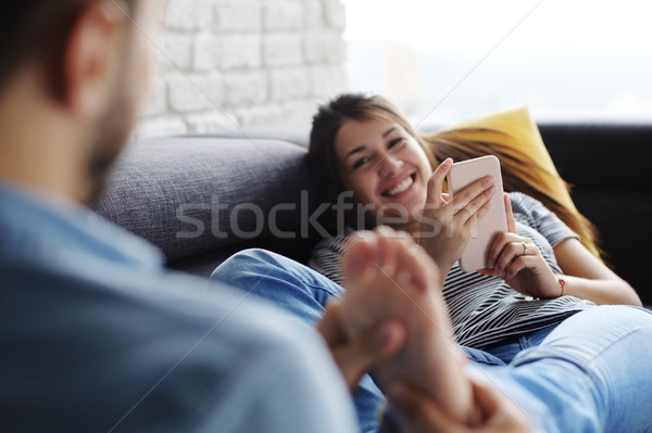 Man Massaging Girlfriend Feet On Sofa At Home Stock photo © diego_cervo