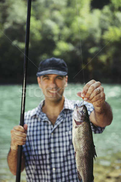 man fishing on river and showing fish to the camera Stock photo © diego_cervo