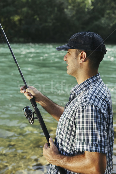 Fisherman standing near river and holding fishing rod Stock photo © diego_cervo