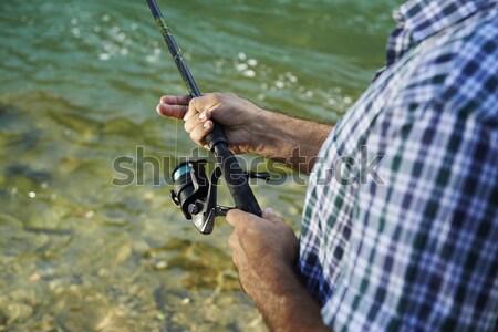 Fisherman standing near river and holding fishing rod Stock photo © diego_cervo
