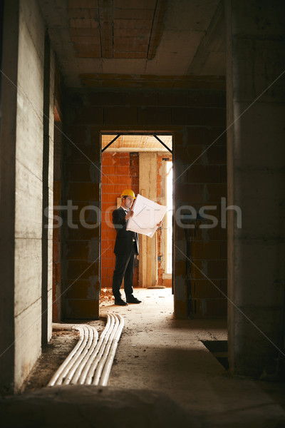 Architect standing in house under construction with building pla Stock photo © diego_cervo
