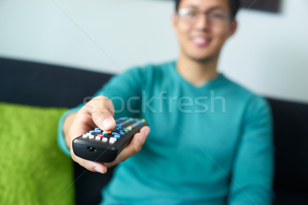 Asian Man Watching TV Changes Channel With Remote Stock photo © diego_cervo