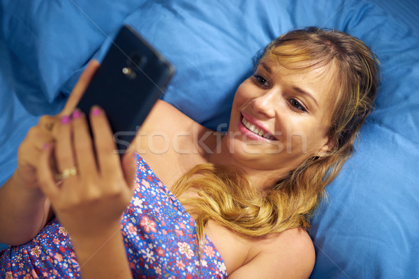 Girl In Bed Reading Love Phone Message From Boyfriend Stock photo © diego_cervo