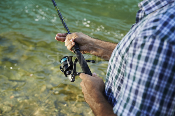 Fisherman standing near river and holding fishing rod Stock photo © diego_cervo