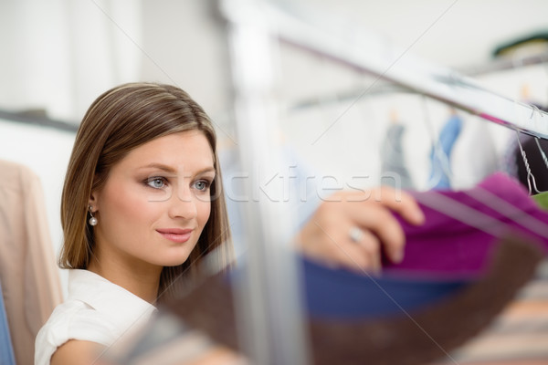 Stock photo: young woman choosing shirt in clothes shop