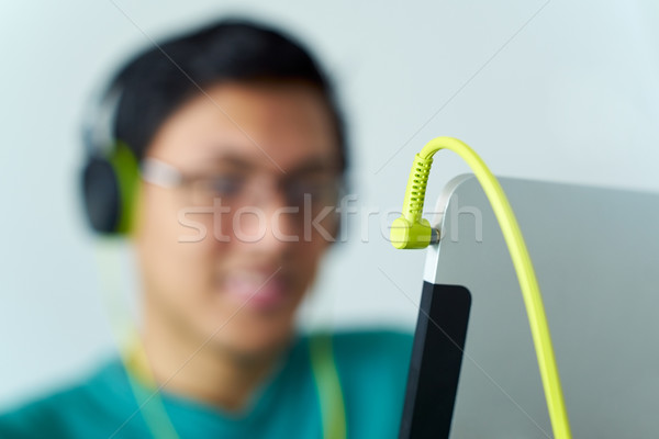 Stock photo: Asian Man With Green Headphones Listens Podcast Tablet PC