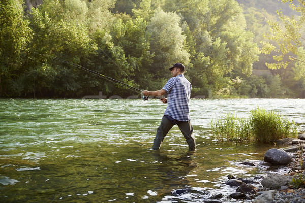 Fisherman standing near river and holding fishing rod Stock photo © diego_cervo