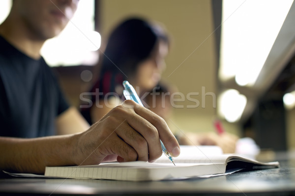 Stock photo: young man doing homework and studying in college library
