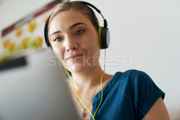 Stock photo: Woman With Green Earphones Listens Podcast Music On Tablet