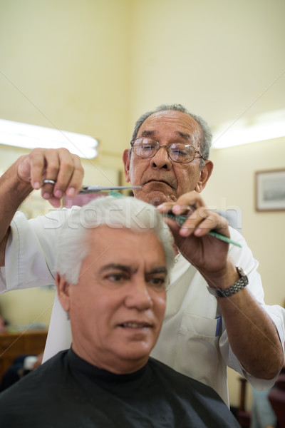 Old barber cutting hair to client in barber shop Stock photo © diego_cervo