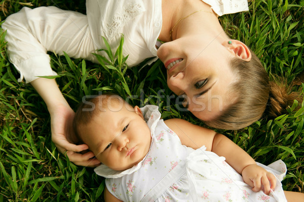 Stock photo: Mother With Caressing Baby Daughter Laying On Grass