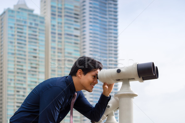 Asian business man with binoculars looking at city Stock photo © diego_cervo