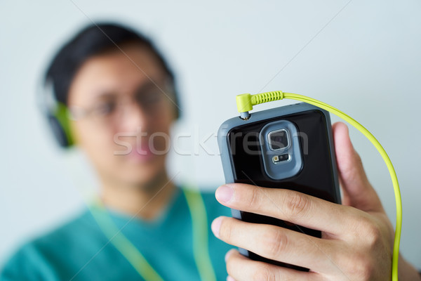 Chinese Man With Green Headphones Listens Music Podcast Phone Stock photo © diego_cervo
