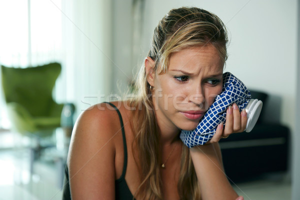 Stock photo: Young woman with toothache holding ice bag on cheek