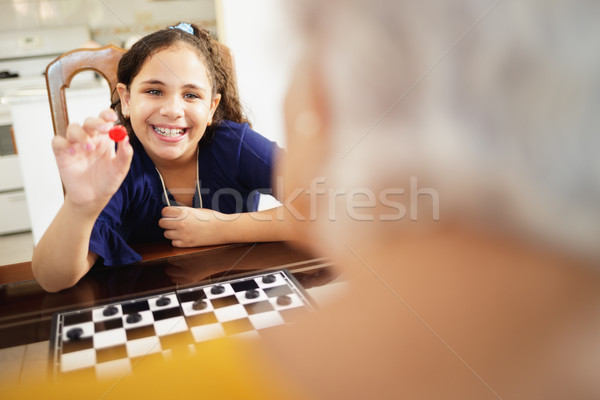 Nagymama játszik társasjáték leányunoka otthon boldog Stock fotó © diego_cervo