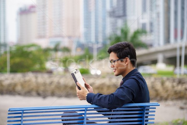 Portrait of asian office worker with ipad on bench Stock photo © diego_cervo