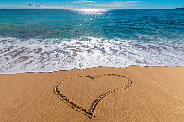 Drawing heart on the sand in the beach Stock photo © digoarpi