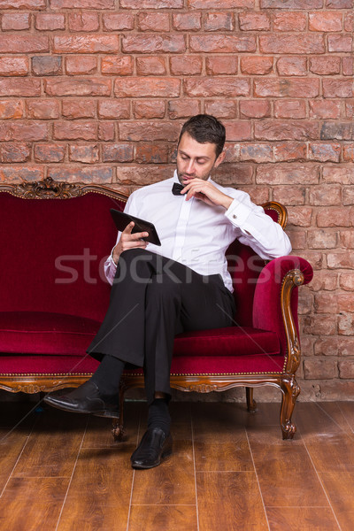 Businessman lying on a settee and reading tablet Stock photo © Discovod