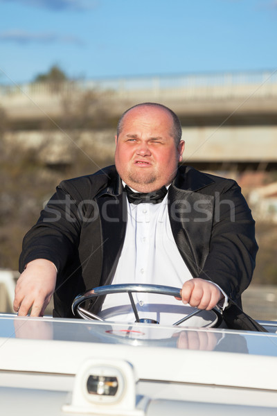 Overweight man in a tuxedo at the helm of a pleasure boat Stock photo © Discovod