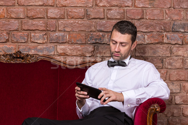 Businessman lying on a settee and reading tablet Stock photo © Discovod