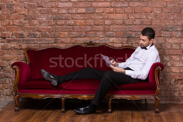 Businessman lying on a settee and reading paperwork Stock photo © Discovod