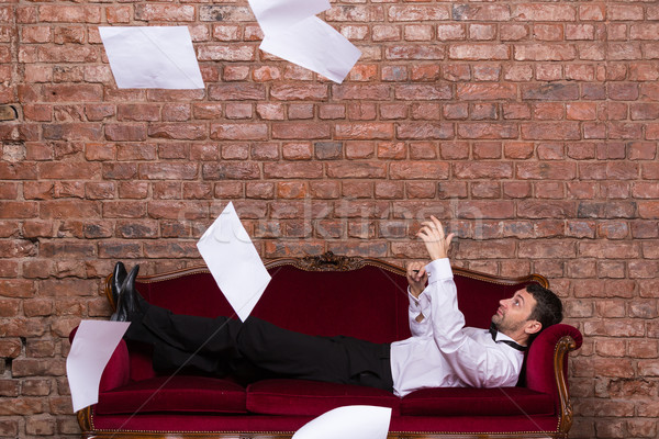 Businessman lying on a settee with flying papers Stock photo © Discovod