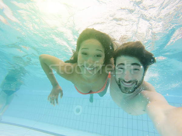 Handsome couple taking selfie under the water in swimming pool r Stock photo © DisobeyArt