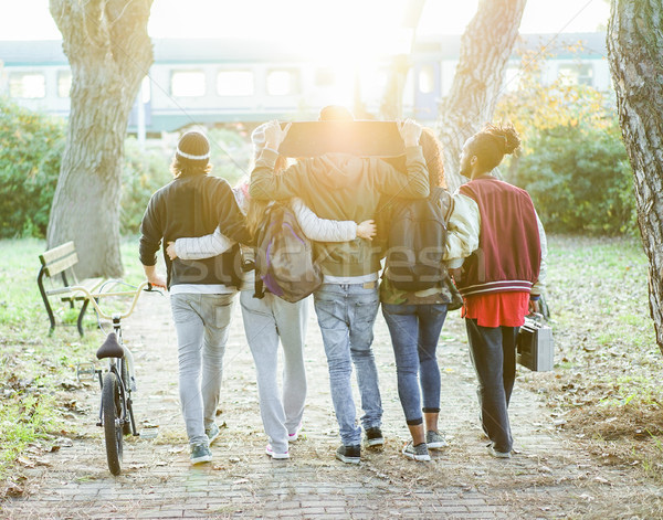 Group of friends walking in city park with train and sun light i Stock photo © DisobeyArt